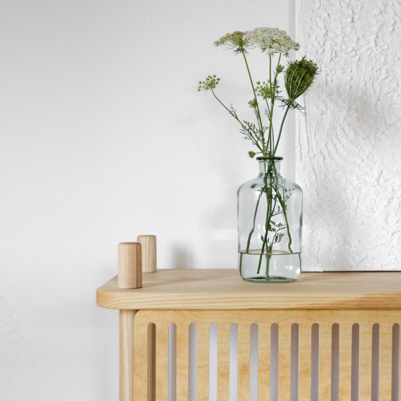 Detail einer minimalistischen Einrichtung mit einem Regal aus Esche Massivholz und darauf stehend eine Vase mit Blumen und ein Gemälde
